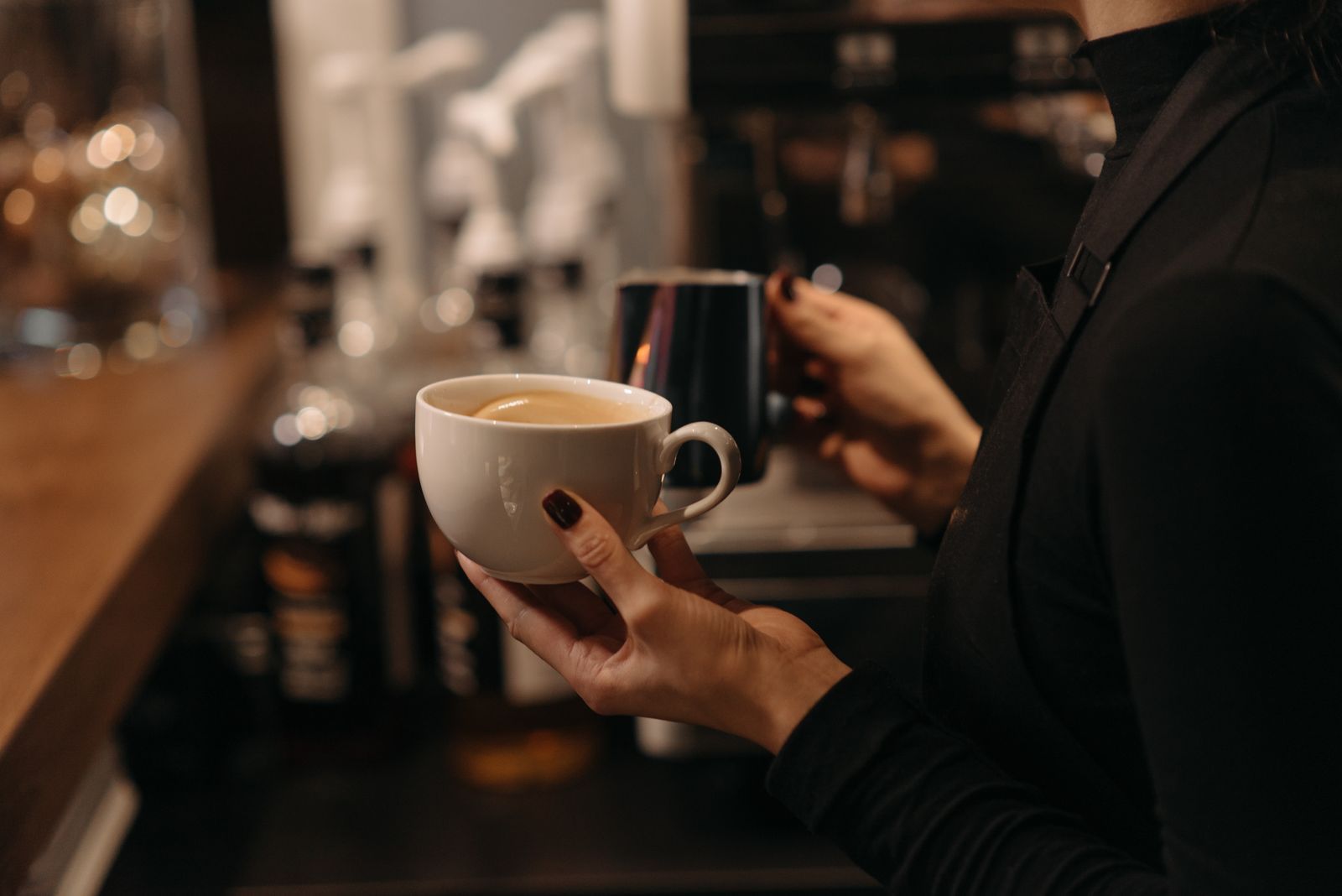 Barista holding a cup while preparing coffee behind the counter